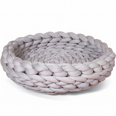 Skein round knitted flexible grey cat bed on a plain white background