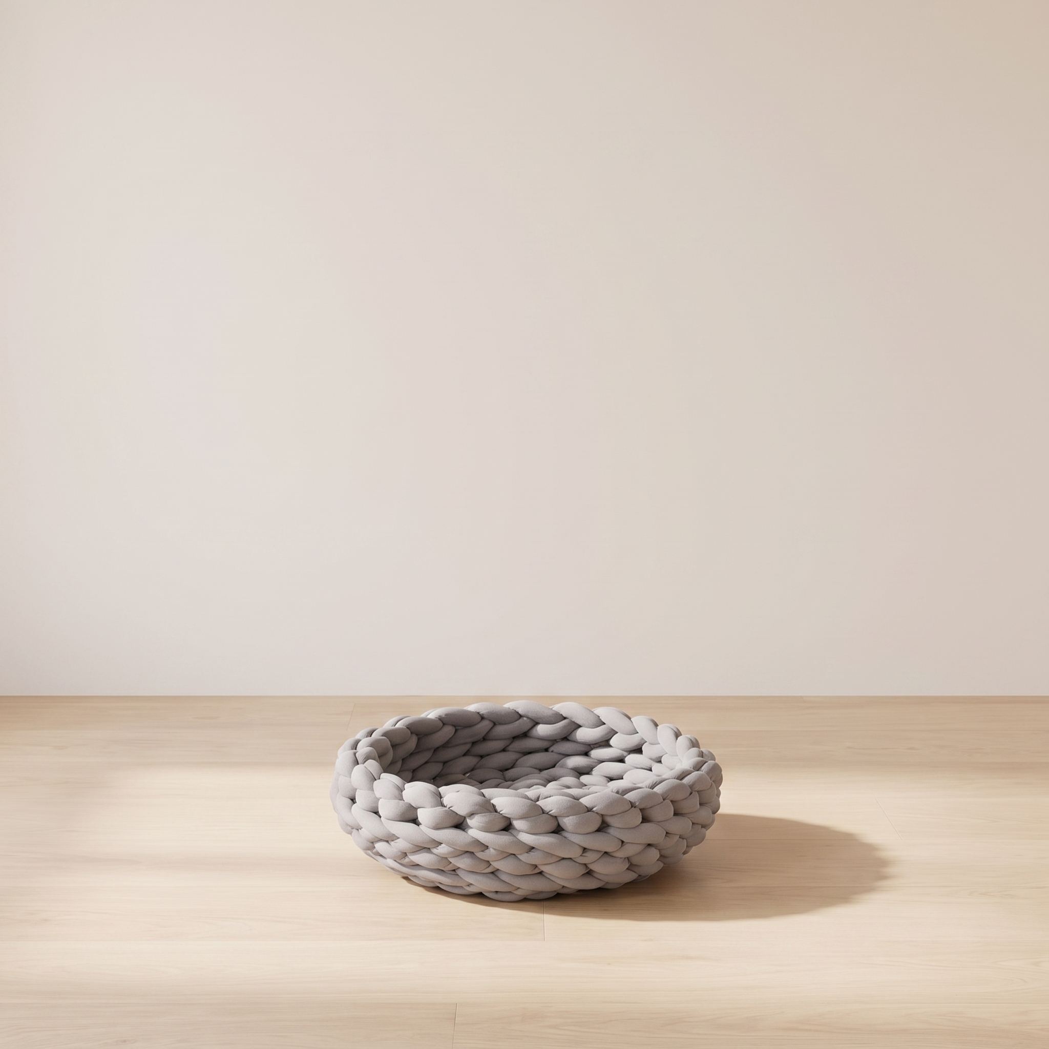 Skein knitted grey cat bed in a minimal room against a warm off-white wall